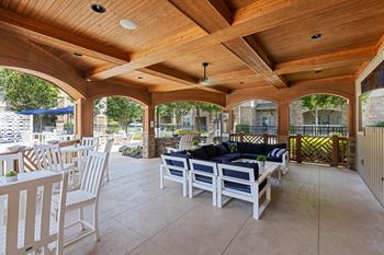 a covered patio with a wooden ceiling and white furniture